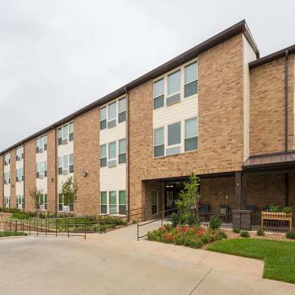 a brick apartment building with a parking lot in front.