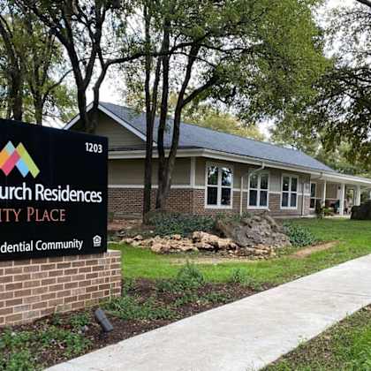 a sign for national church residences trinity place, a senior residential community, is displayed in front of a building.
