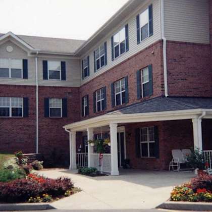 a red brick building with a white porch and a white picket fence.