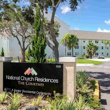 the sign in front of the building reads national church residences the courtnery.