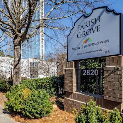 a sign for parish grove apartments sits in front of a tree and shrubs.