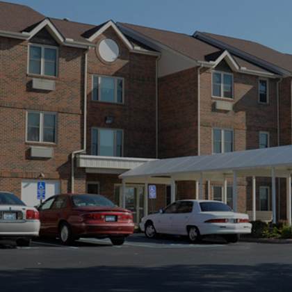 a parking lot in front of a brick building with cars parked.