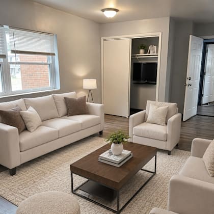 a living room with a white sofa, a white chair, a brown coffee table, and a white rug.