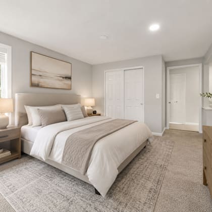 a bedroom with a large bed, a nightstand with a lamp, and a painting on the wall.
