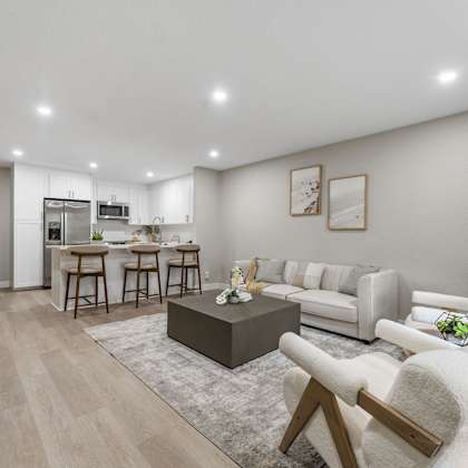 a modern living room with a kitchen in the background at tamarack sands apartment homes, carlsbad, ca