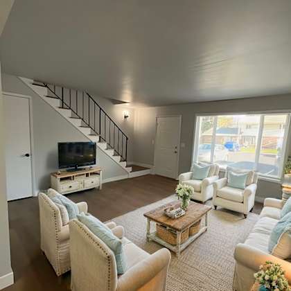 a living room with a staircase and a television.