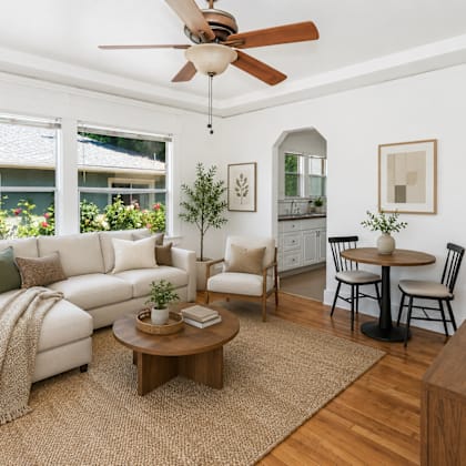 a living room with a white couch, a wooden coffee table, and a ceiling fan.