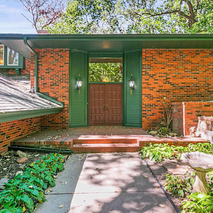 a red brick house with a green door and steps leading to the entrance.