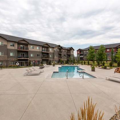a swimming pool surrounded by lounge chairs and apartment buildings.