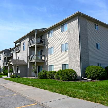apartment building with a parking lot in front.
