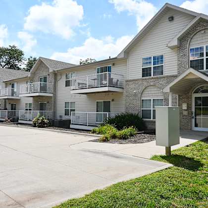 apartment complex with a grey and white building and a sign on the grass.
