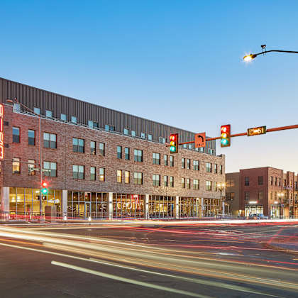 a long exposure shot of a street with a red traffic light and a building in the background.