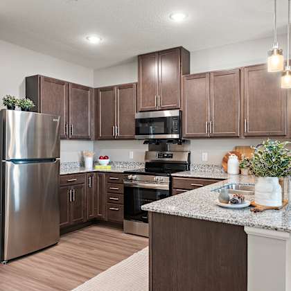 a kitchen with brown cabinets and a stainless steel refrigerator.at decatur landing i & ii, brooklyn park, mn 55445