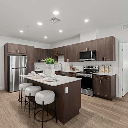 a modern kitchen with dark brown cabinets and a white island.