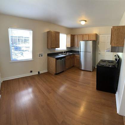 an empty kitchen with wooden floors and stainless steel appliances