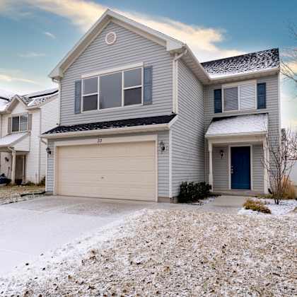 a house with a garage door and a snow covered driveway