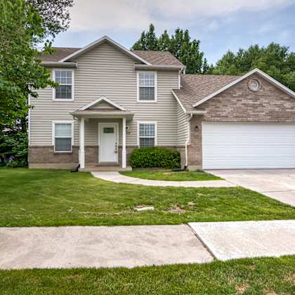 a beige house with a white garage door and a lawn