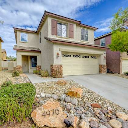a beige house with a yard with rocks on the ground