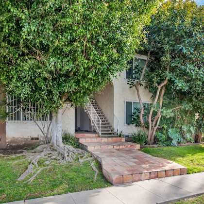 a house with stairs and a tree in front of it