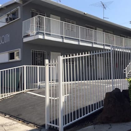 a modern house with a white fence and a staircase leading to the entrance.