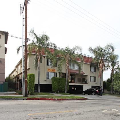 a building with palm trees in front of it on a street