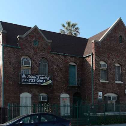 a brick building with a sign that says "now selling" and a phone number.