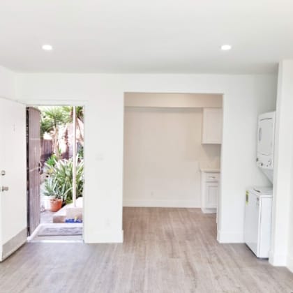 an empty living room with a door to a kitchen
