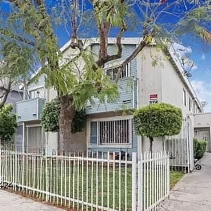 a white house with a white fence and a tree in front of it