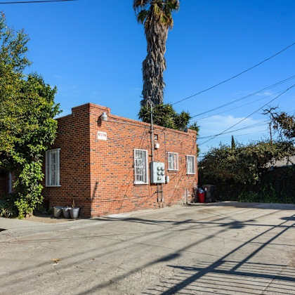 an old brick building on a street with a palm tree