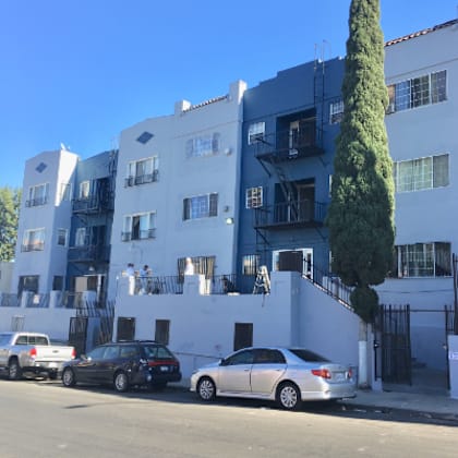 the side of a white building with cars parked in front