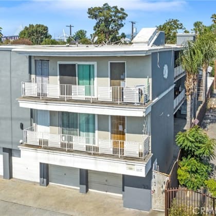 a grey two-story apartment building with a balcony on the second floor.
