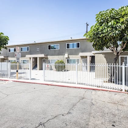 a building with a white fence and a tree in front.