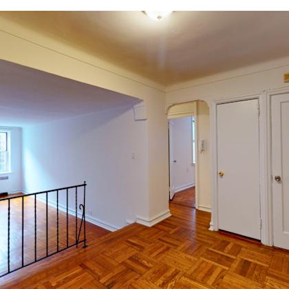 a room with a balcony and wooden floors.
