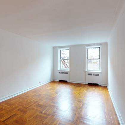 a room with wooden floors and two windows.