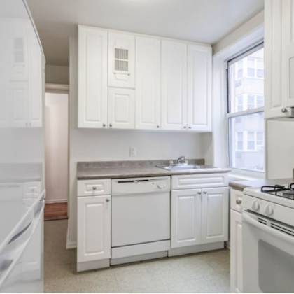 a white kitchen with a refrigerator, oven, and microwave.