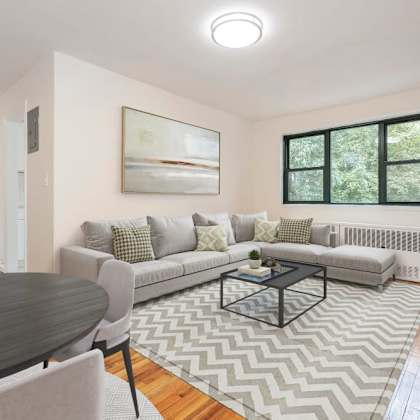 a living room with a grey couch, a coffee table, and a painting on the wall.