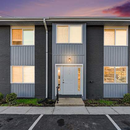 a grey building with a white door and windows.