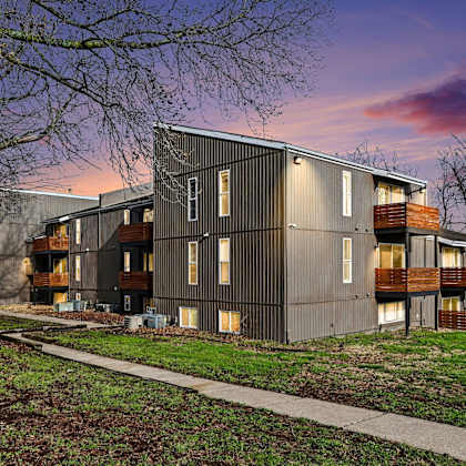 a modern apartment building with a grassy area in front.