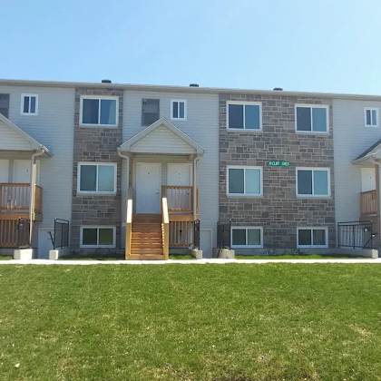 a large apartment building with a grassy front yard.