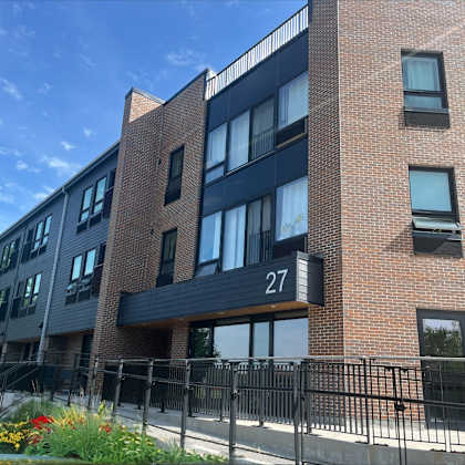 a brick apartment building with a black railing and a gate