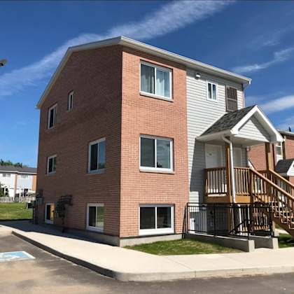 a brick apartment building with a porch and stairs
