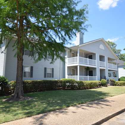 a white two-story house with a tree in front.
