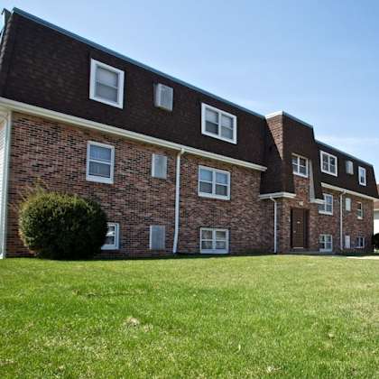 a brick apartment building with a green lawn