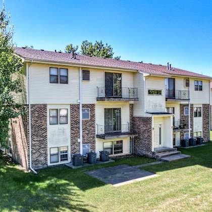 an apartment building with a lawn and trees in front of it