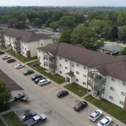 an aerial view of an apartment complex with cars parked on the street