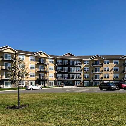 a large apartment complex with a parking lot in front.