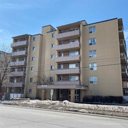 a large apartment building with a parking lot in front.