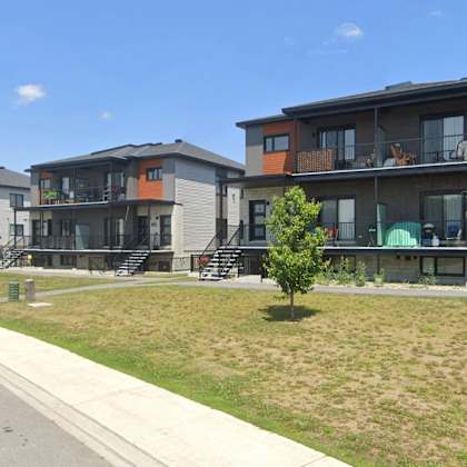 a row of modern townhouses with a street in front.