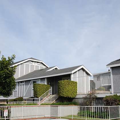a row of houses with a white fence in front.