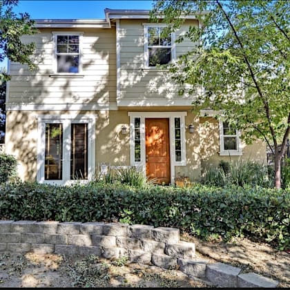 a two-story house with a stone wall in front.